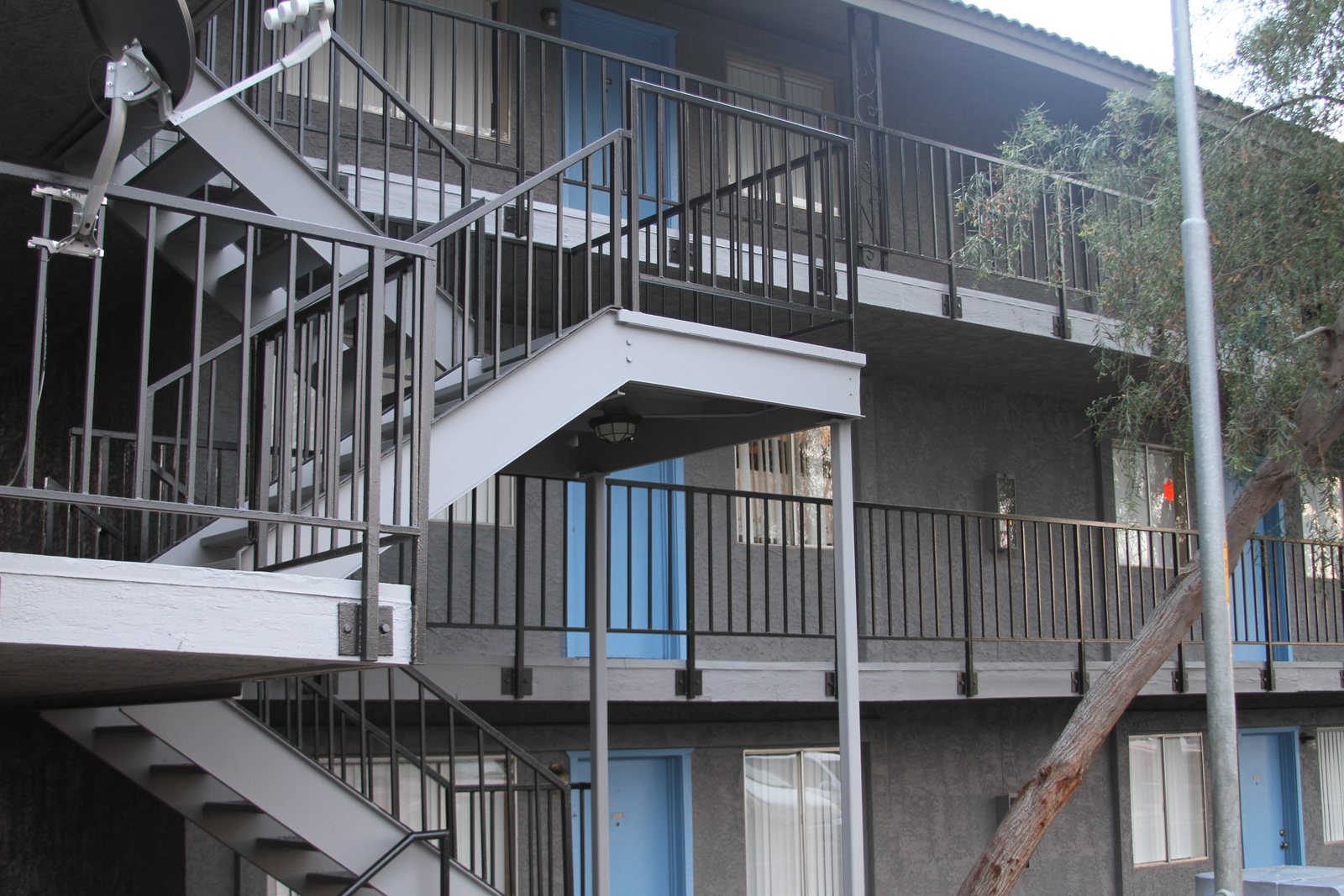 Freshly painted steel stairways, railings and walkways at the same apartment community, with unit doors in blue