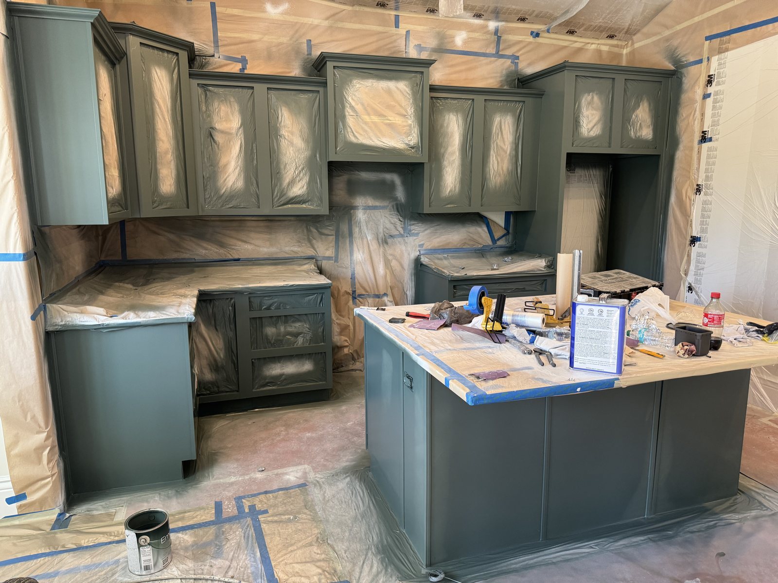 Kitchen cabinets masked and freshly sprayed sage green during cabinet refinishing by Happy Brush Painters