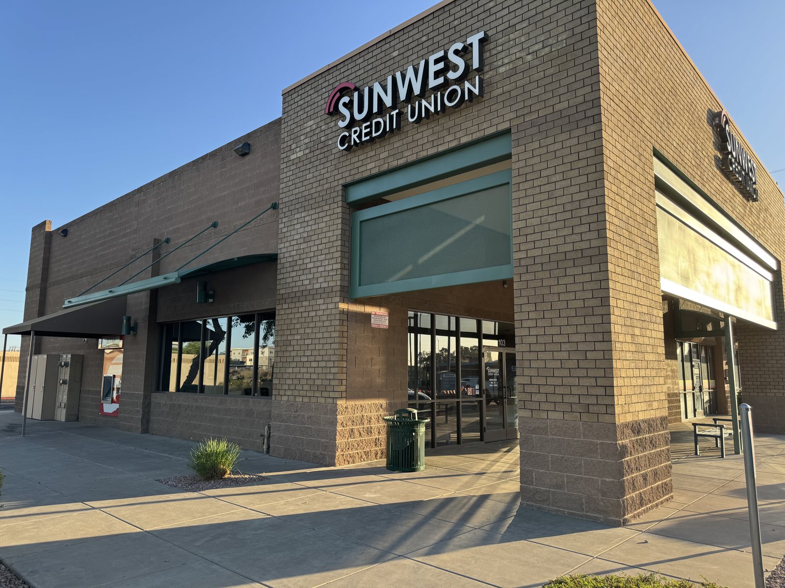 Credit union branch building in Arizona painted by Happy Brush Painters &mdash; tan masonry with a dark lower accent band and entry canopy