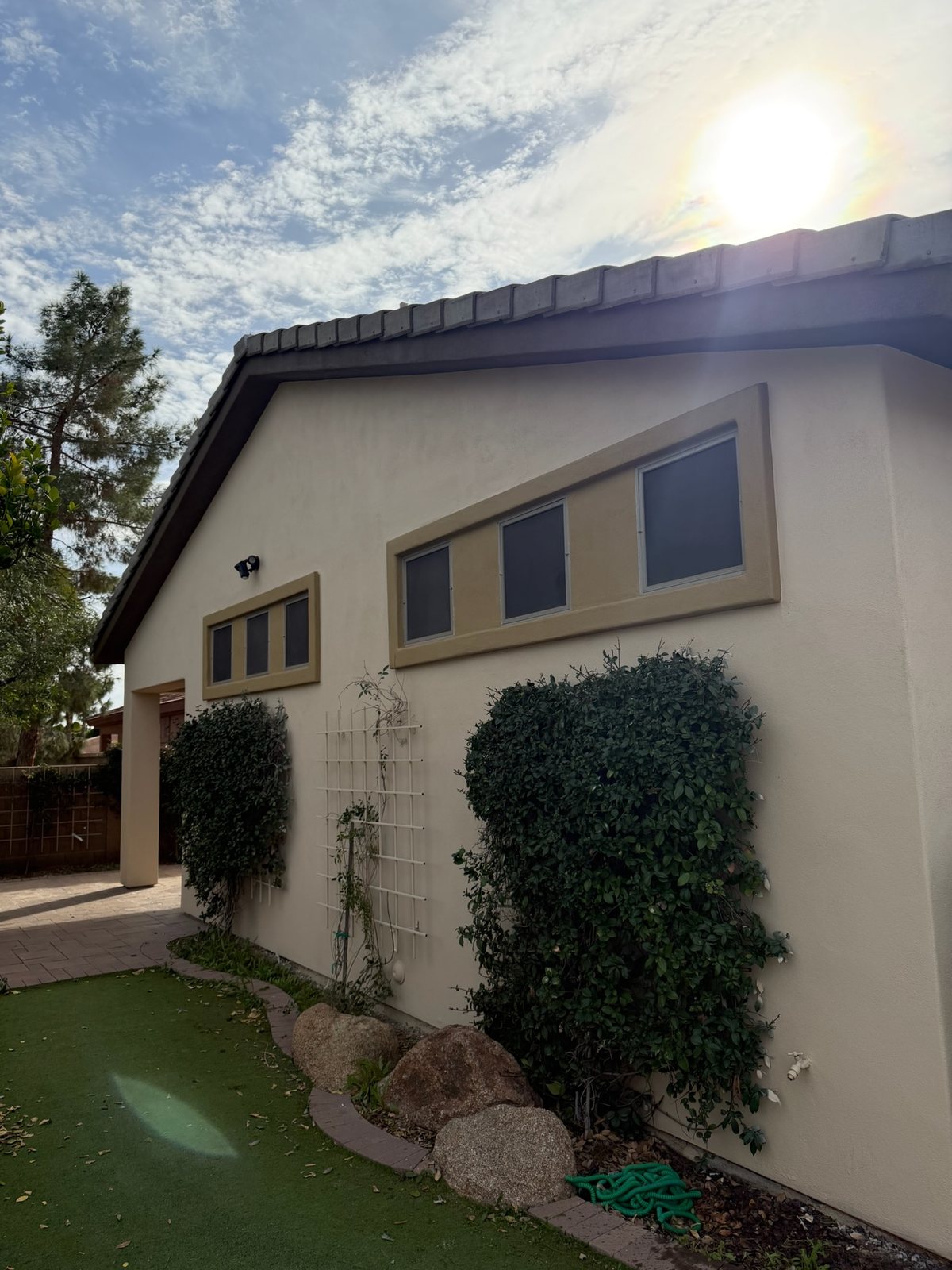 Side elevation of an Arizona home after an exterior repaint &mdash; cream stucco with the window surrounds painted a contrasting tan