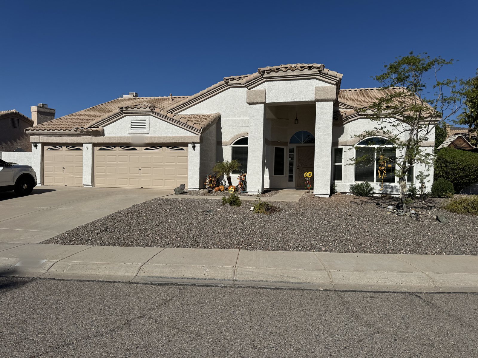 Single-story Arizona home painted by Happy Brush Painters &mdash; cream stucco with tan garage doors, arched entry and a tile roof