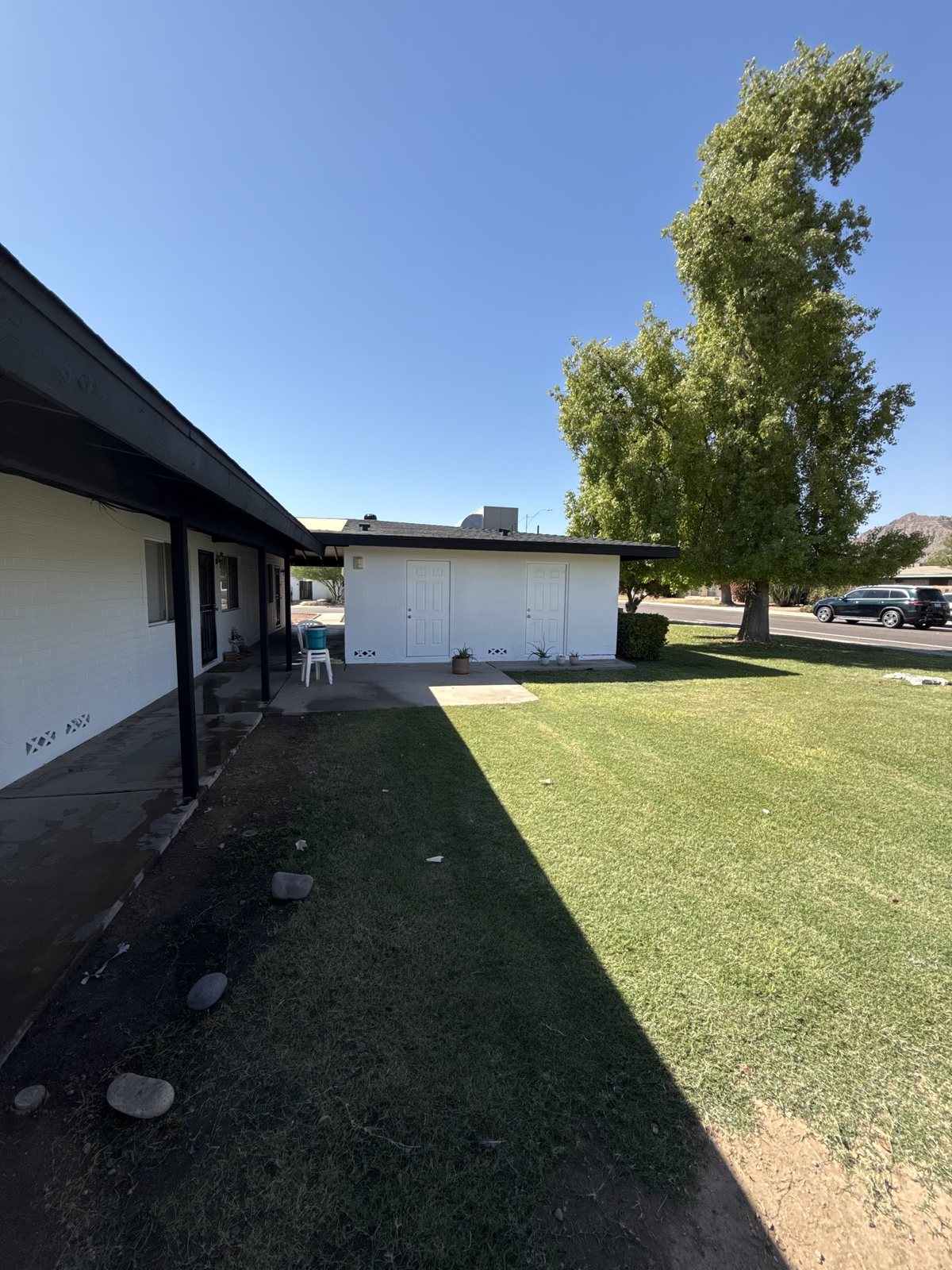 White Arizona home with near-black fascia and eaves, painted by Happy Brush Painters &mdash; white garage doors and a green lawn
