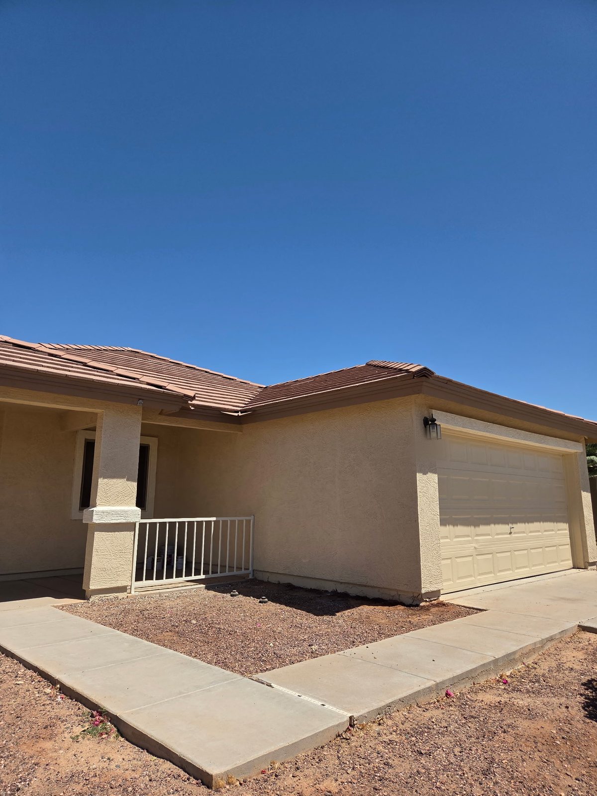 A second tan home on the same street, painted by Happy Brush Painters &mdash; stucco body, garage surround and porch column
