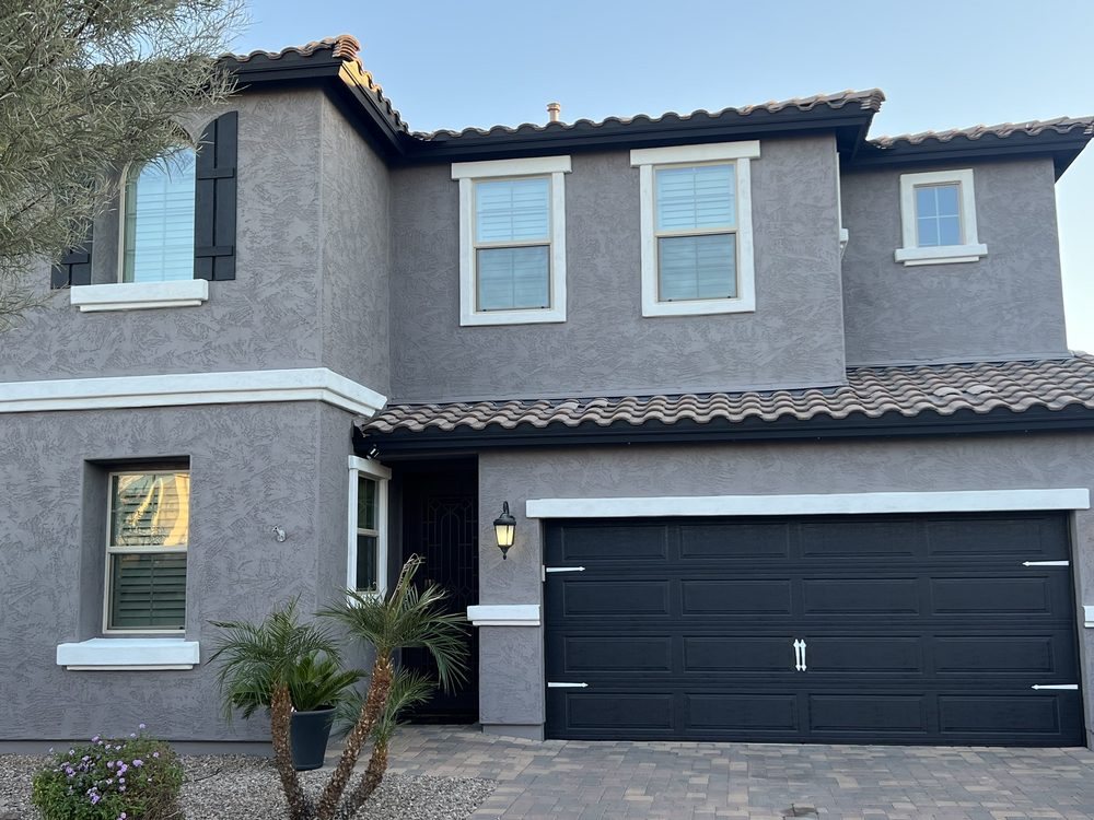 Grey two-story Arizona home painted by Happy Brush Painters &mdash; white trim, black garage door and paver driveway