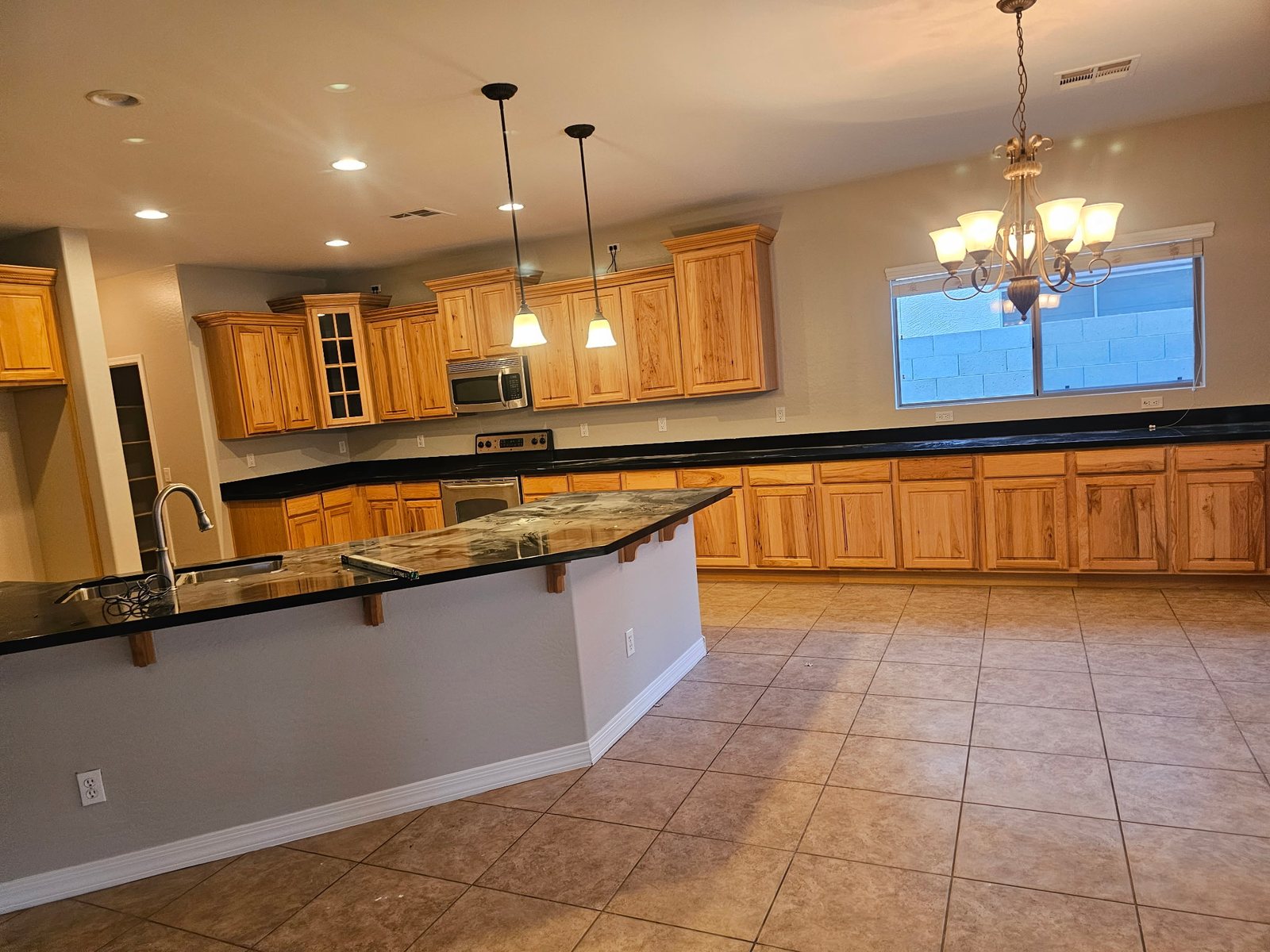 Kitchen and great room after an interior repaint &mdash; walls and ceiling in a light neutral around wood cabinets and granite counters