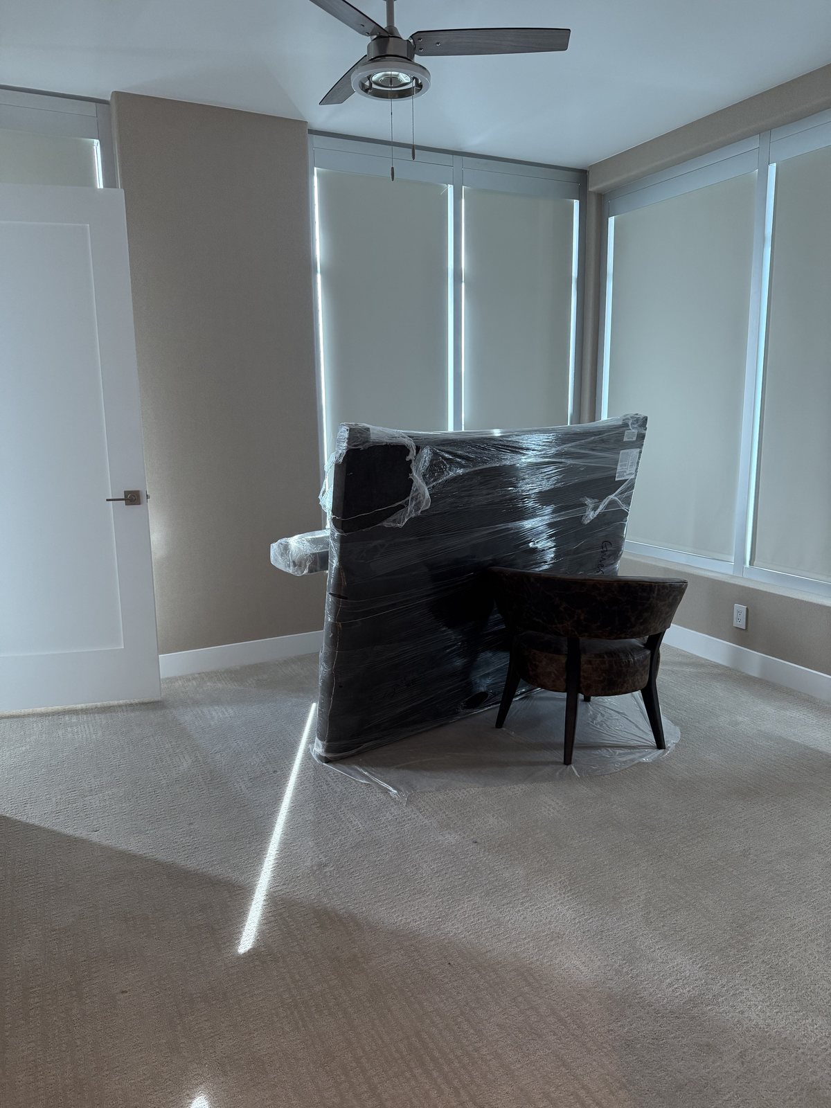 Furniture wrapped in protective plastic and carpet covered before an interior repaint by Happy Brush Painters