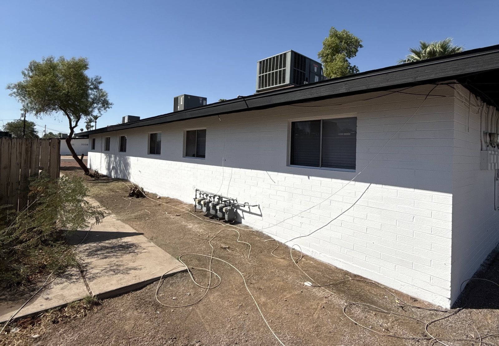 Multi-unit apartment building in Arizona painted by Happy Brush Painters &mdash; white painted block walls, dark fascia and rooftop air-conditioning units