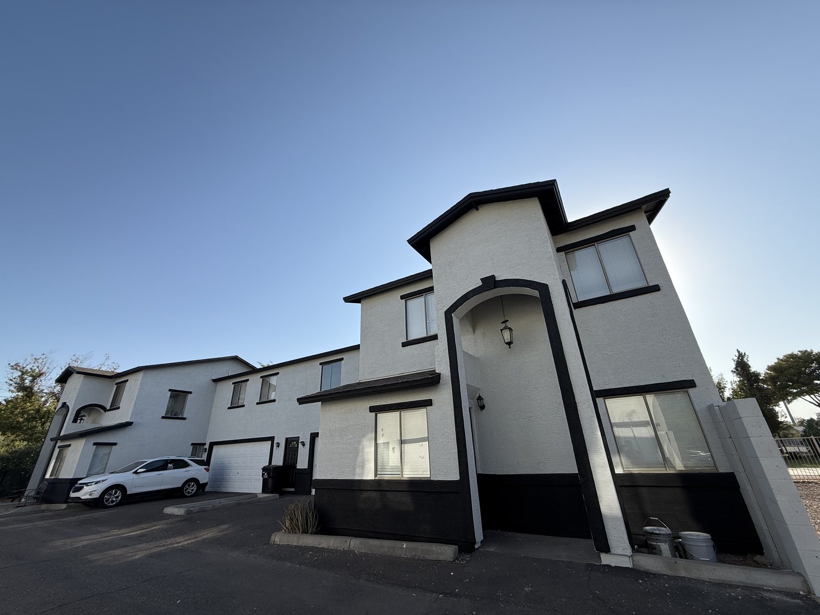 Corner tower and arched entry of the same townhome community, white with black trim